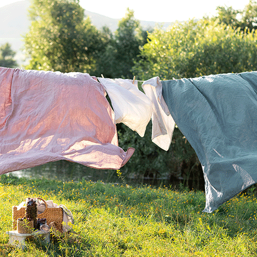 Breathable organic linen sheets for hot sleepers in a minimalist summer bedroom setting.